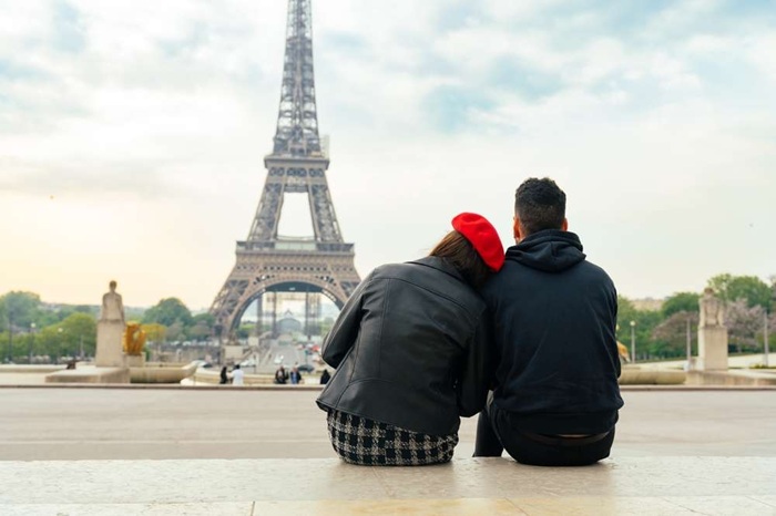 couple de dos assis face à la tour Eiffel