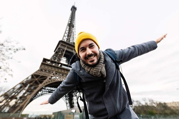 homme avec bonnet et écharpe devant la tour Eiffel