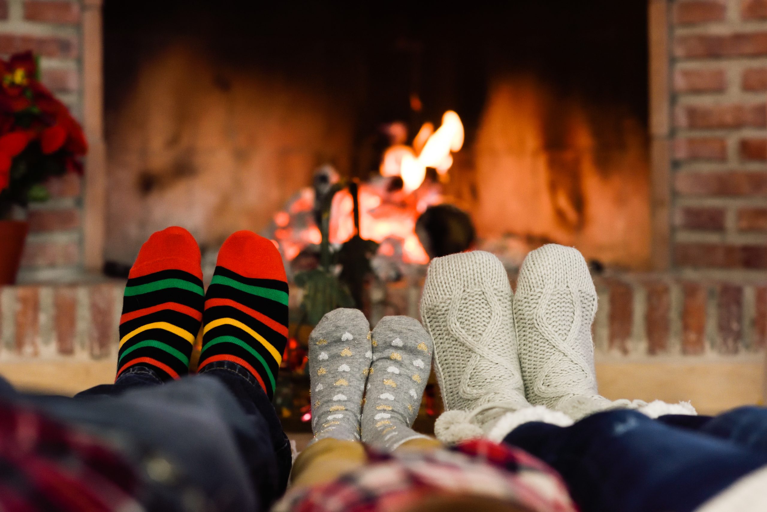 Три пары ног у. Ноги у камина. Уютные носочки. Семья у камина в Рождество. Уют и тепло.