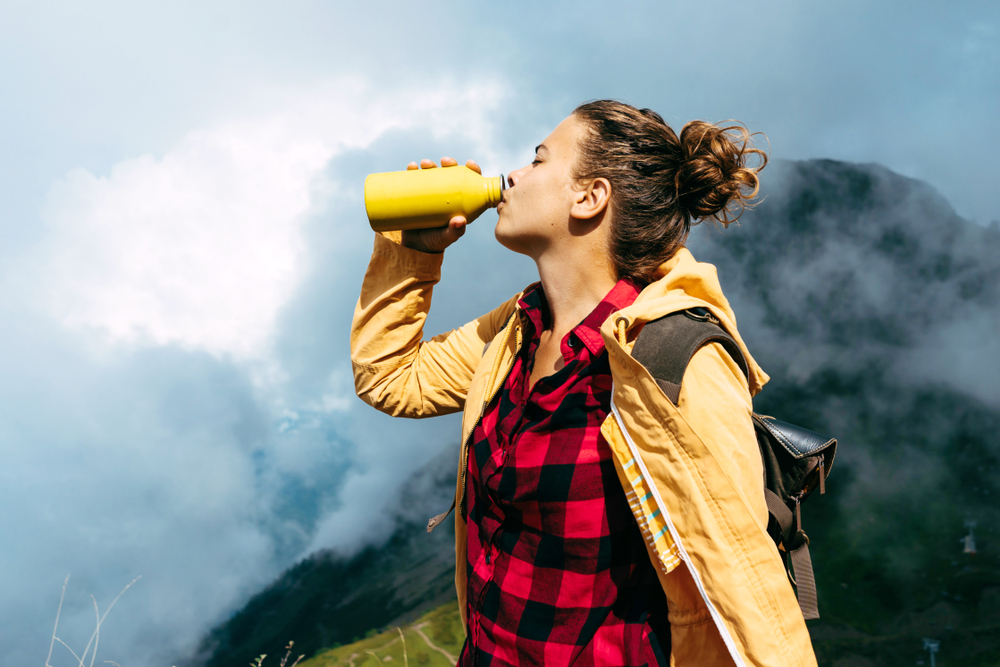 jeune femme boit dans une gourde dans les alpes